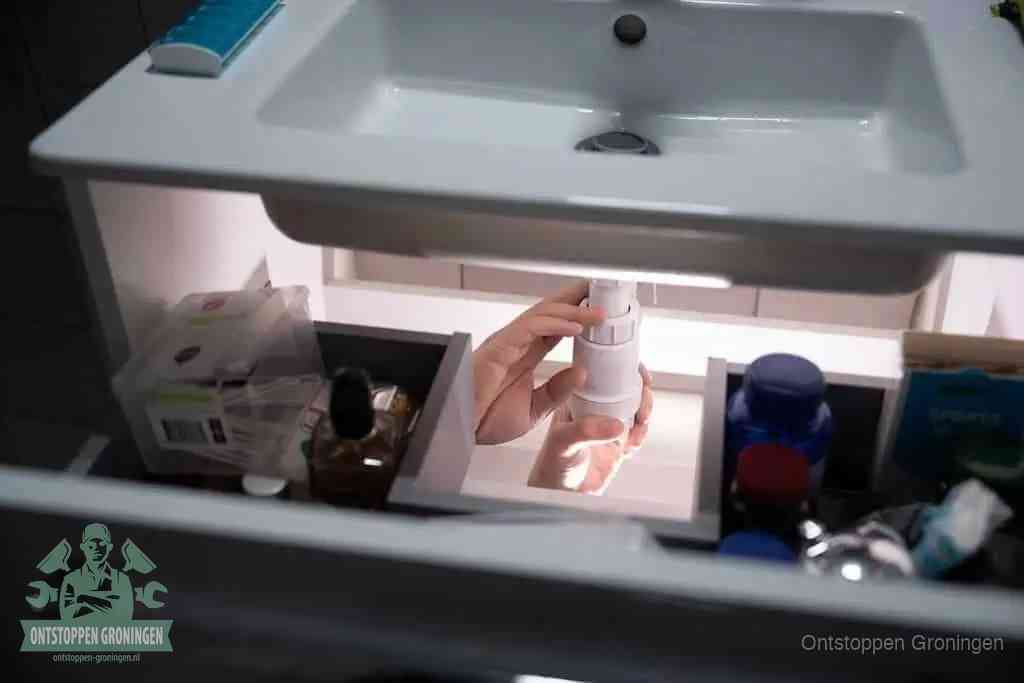 Een pompfles met zeep boven een wastafel, de heet water en afwasmiddel-methode om een vetprop in de afvoer los te maken in Groningen