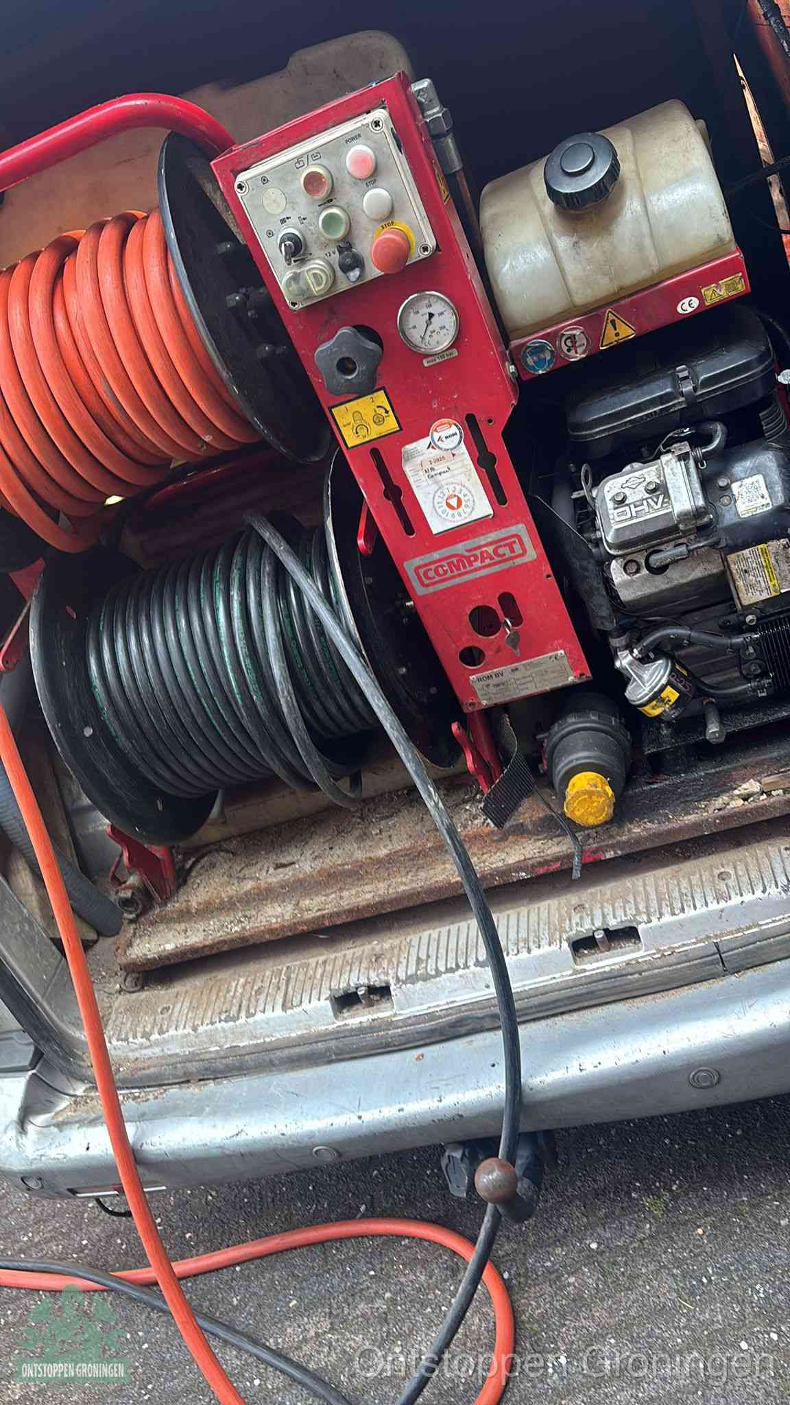 Een rood hogedruk-rioolreinigingstoestel in de laadbak van de bedrijfsbus, apparatuur voor een hardnekkige afvoerverstopping in Groningen