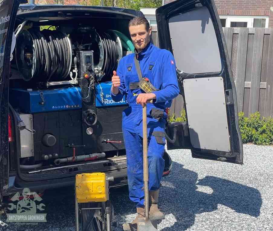 Een monteur bij de werkbus met grote hogedruk-slanghaspels, apparatuur voor hardnekkige afvoerverstoppingen in Groningen