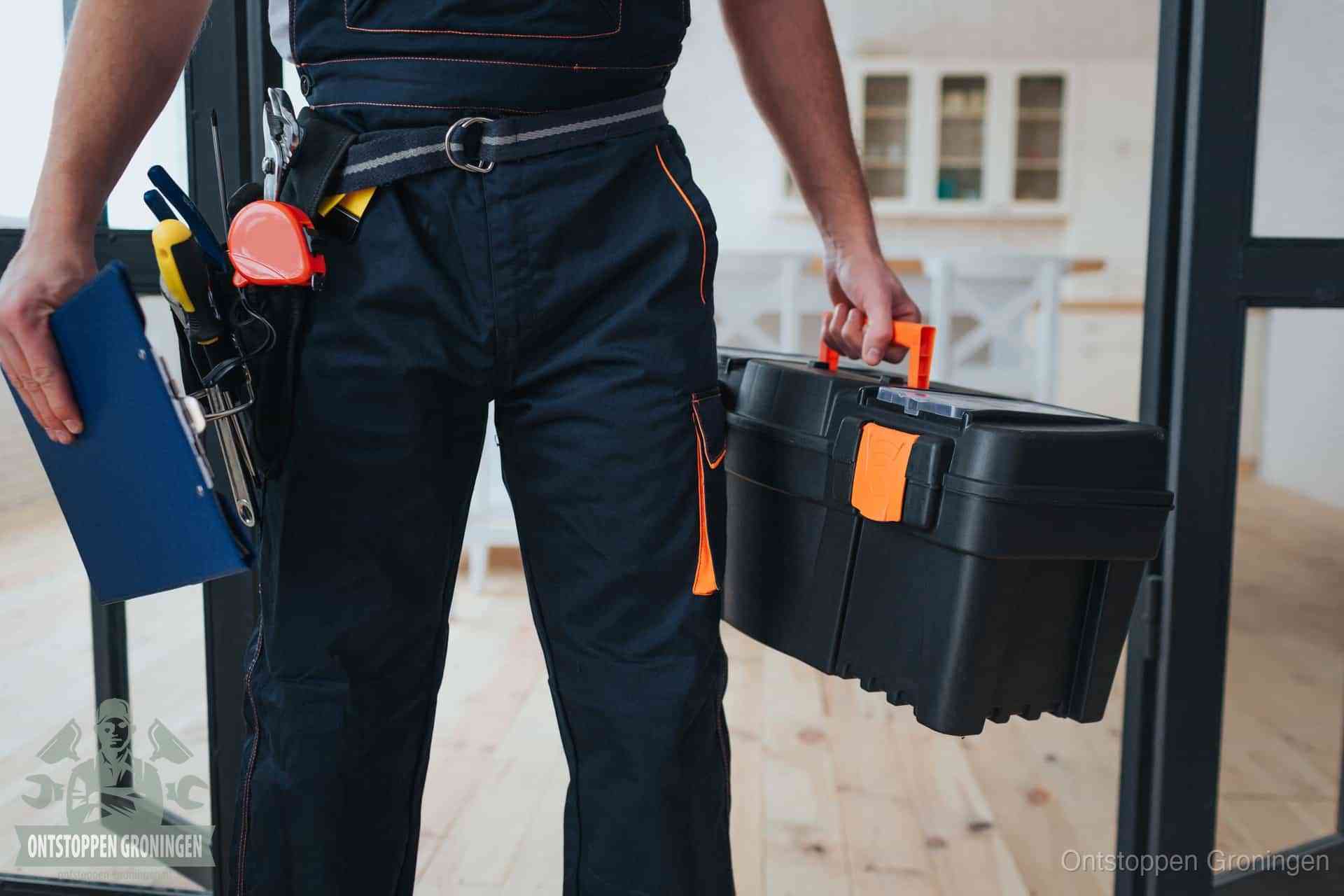 Een monteur met gereedschapsriem en klembord in een keuken, klaar om een transparante prijs voor het gootsteen ontstoppen in Groningen te geven
