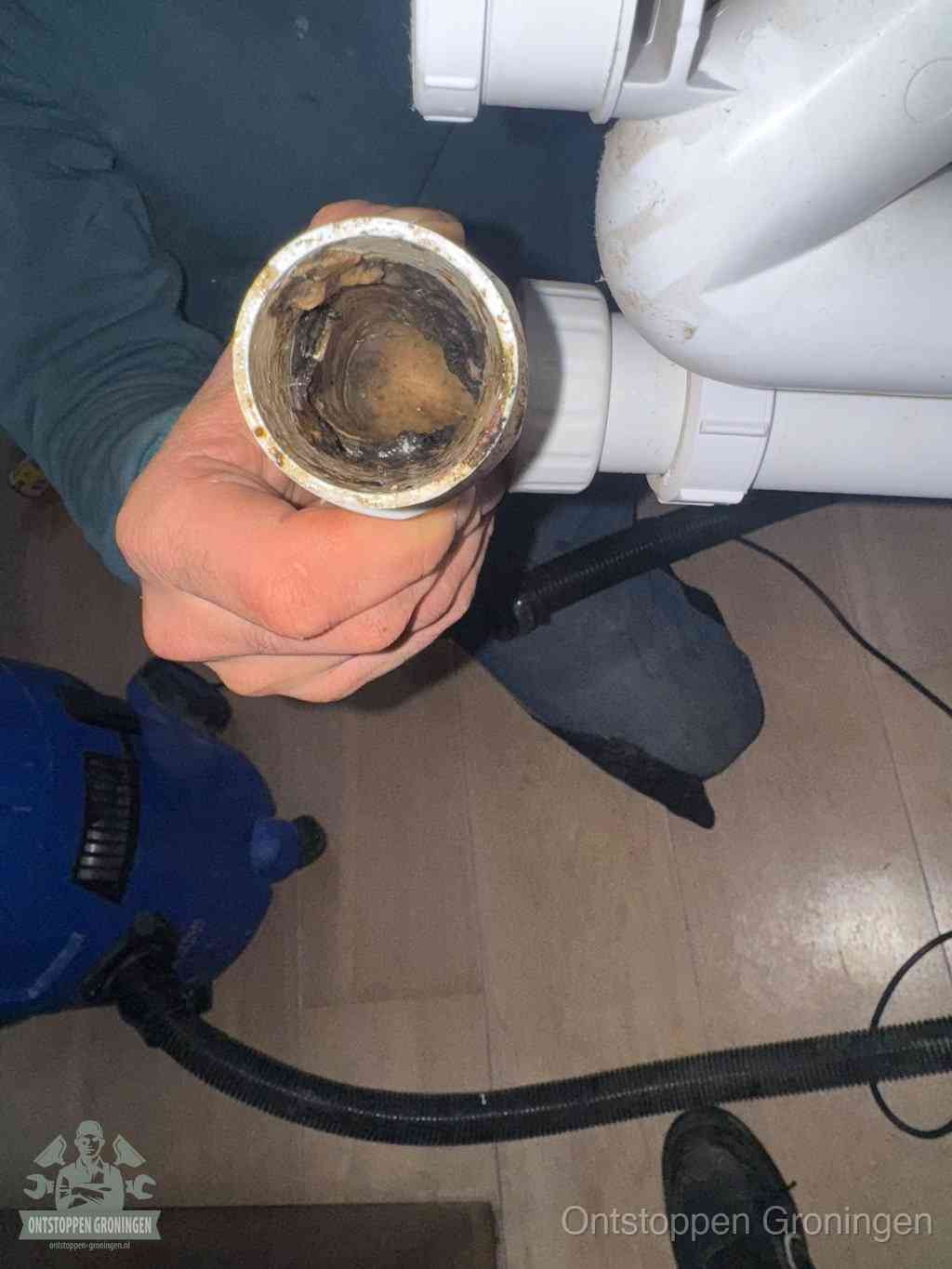 Een losgekoppelde afvoerbuis die van binnen volledig is dichtgeslibd met vet en aanslag, de meest voorkomende oorzaak van een verstopte gootsteen in Groningen