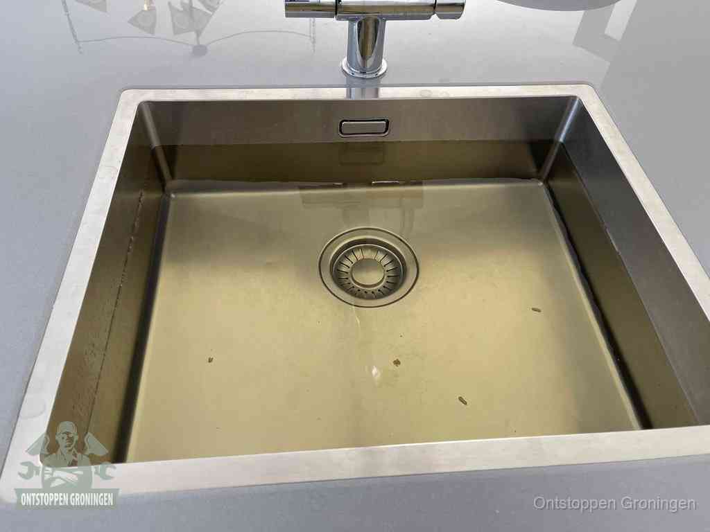 Stilstaand water in een rvs spoelbak dat niet wegloopt, een duidelijk signaal van een gootsteenverstopping in Groningen