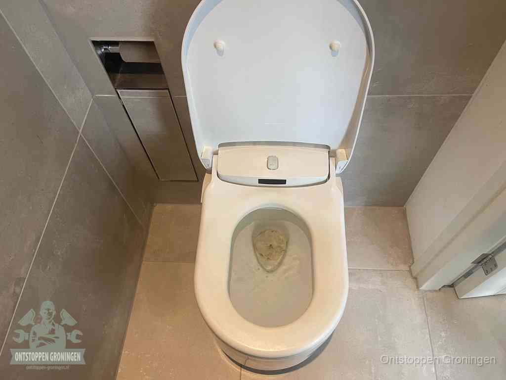 Een wit hangtoilet waarin een prop wc-papier op het water blijft drijven, een duidelijk signaal van een verstopte wc in Groningen