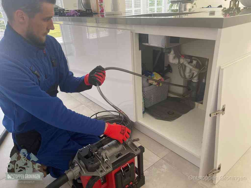 Een monteur reinigt de keukenafvoer grondig met een veermachine om terugkerende gootsteenverstoppingen te voorkomen in Groningen