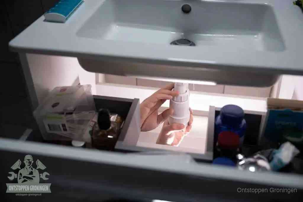 Een pompfles met zeep boven een wastafel in de toiletruimte, de warm water en afwasmiddel-methode om de wc te ontstoppen in Groningen